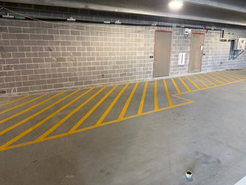 Yellow hatched no-parking zone and blue ADA stall in a parking garage